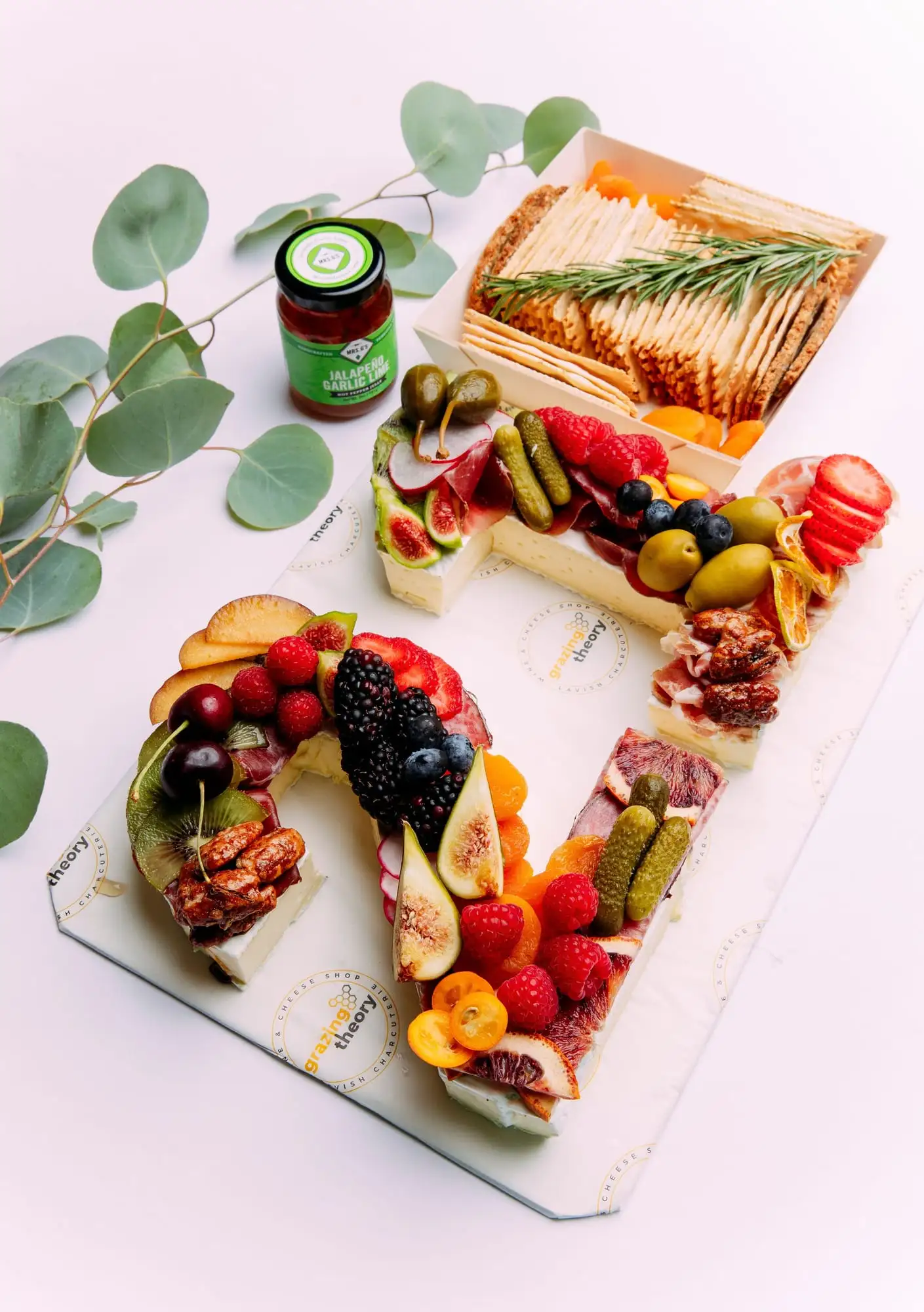 Brie cheese shaped into a number, topped with cured meat, fruit and herbs