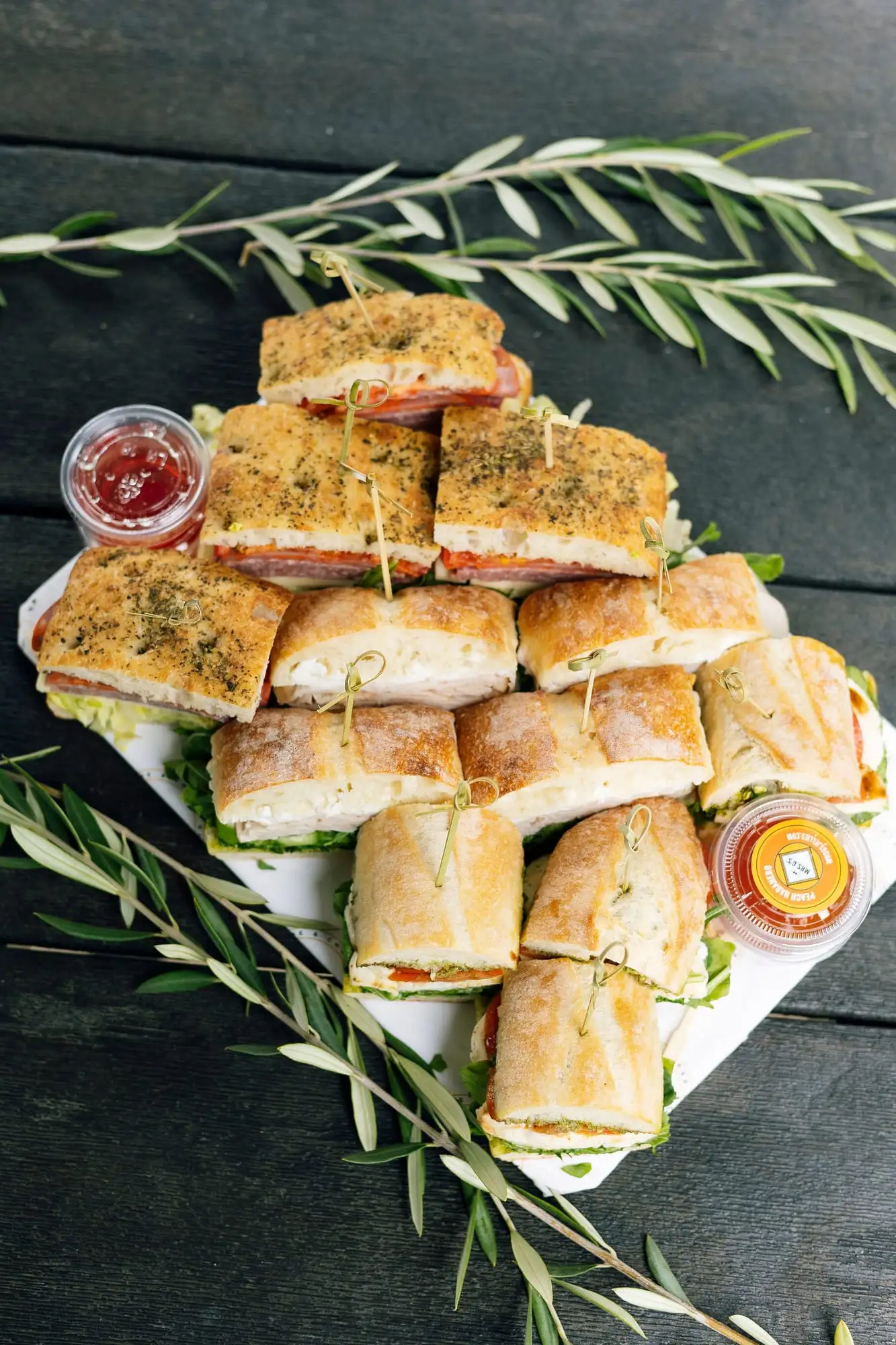 Tray of halved sandwiches wrapped in paper and twine with bags of chips