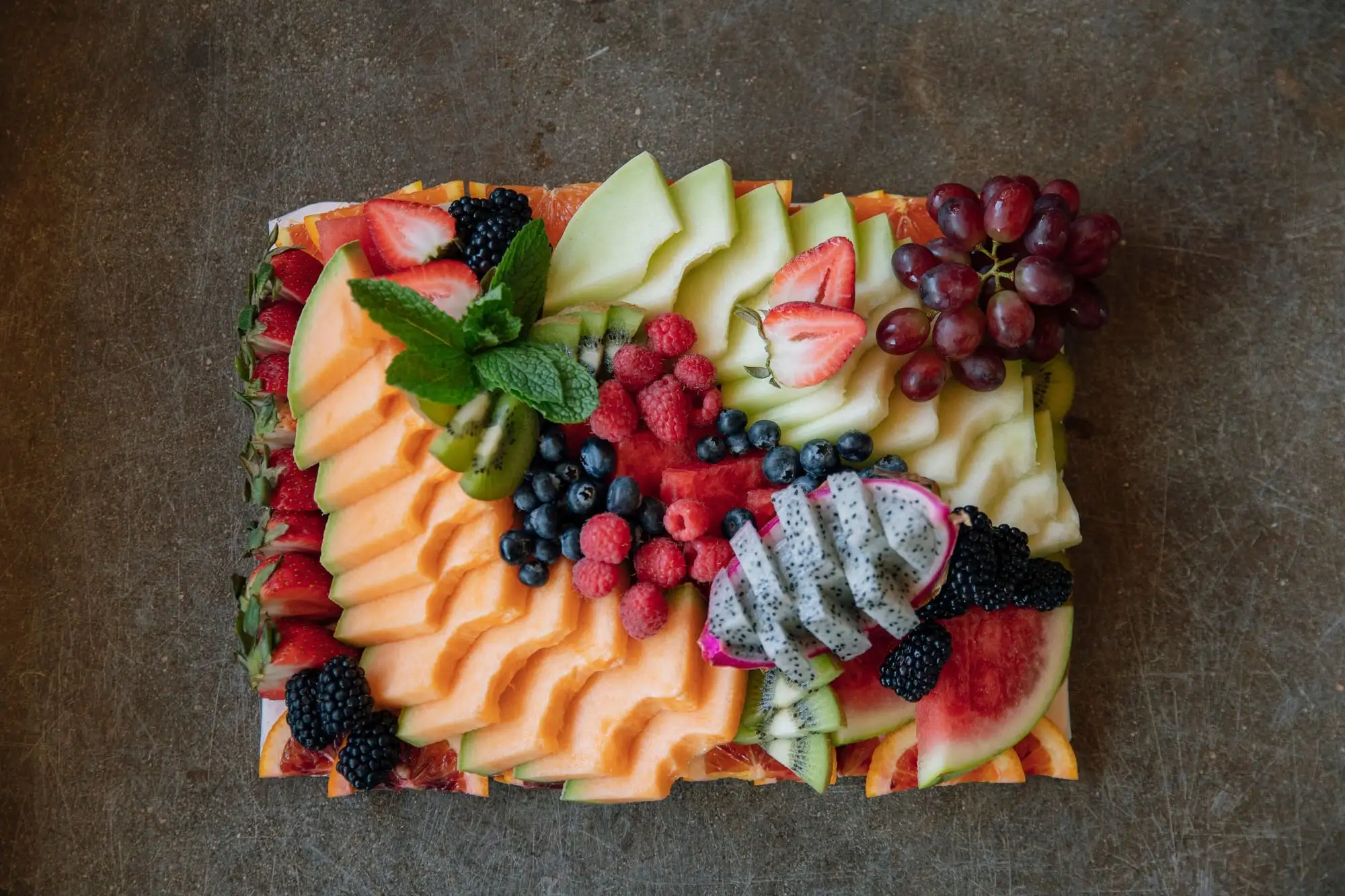 Board of fresh seasonal fruit garnished with herbs
