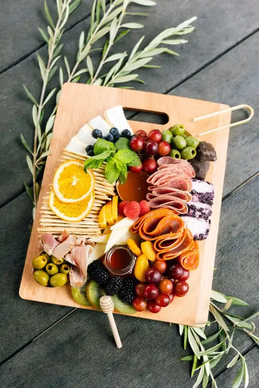 Bamboo board with three cheeses, cured meats, fruit and crackers for 4 to 6 people