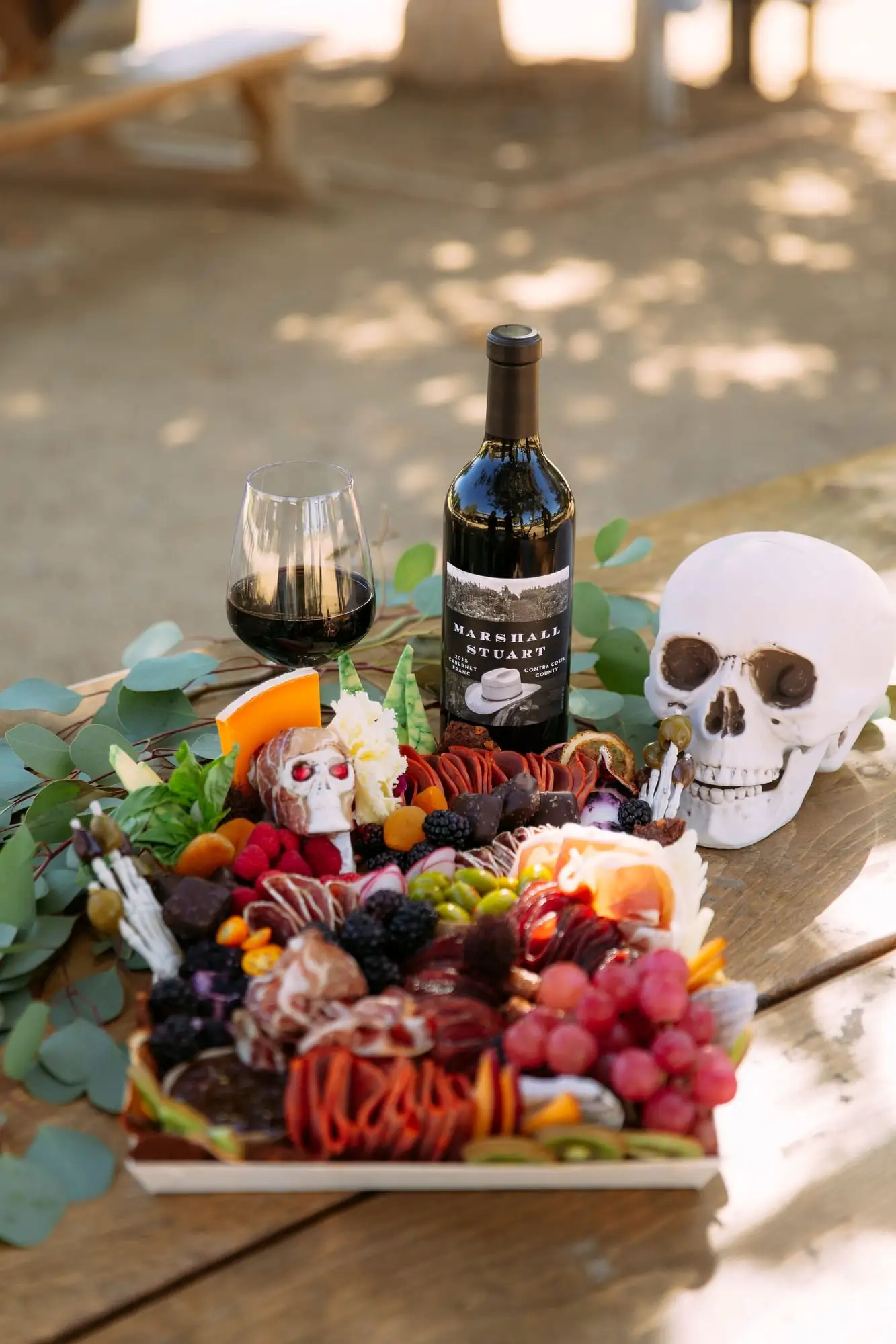 Skeleton charcuterie board for Halloween with a cheese tombstone, salami arms and olive fingers